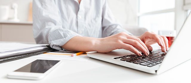 Mlada žena koristi latop tastaturu za pisanje različitih izveštaja