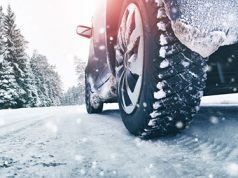 Vozač vozi automobil kroz teško prohodne puteve na planini dok pada sneg. Iza sebe ostavlja trag zimskih guma