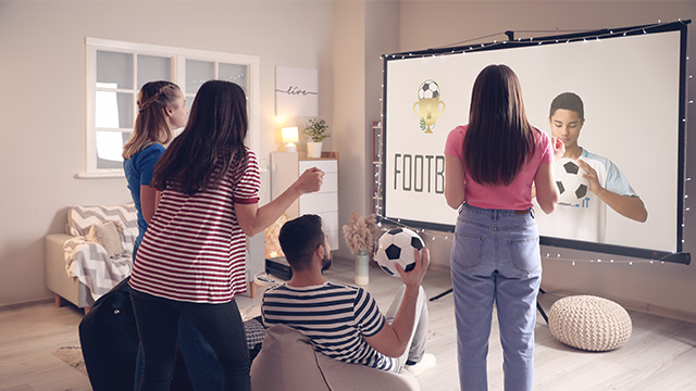 Mlado društvo sedi za projektorom i gleda fudbalsku utakmicu